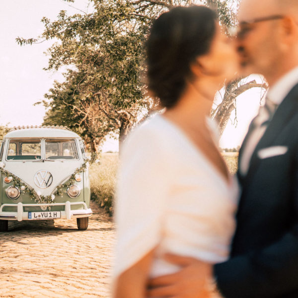 küssendes Hochzeitspaar vor VW Bulli Hochzeitsoldtimer aus Leipzig