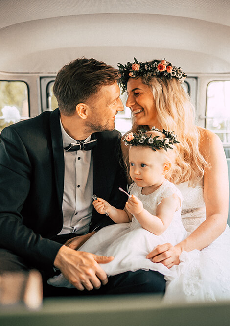 Glückliches Hochzeitspaar in VW Bulli von Sundriver mit ihrem Kind